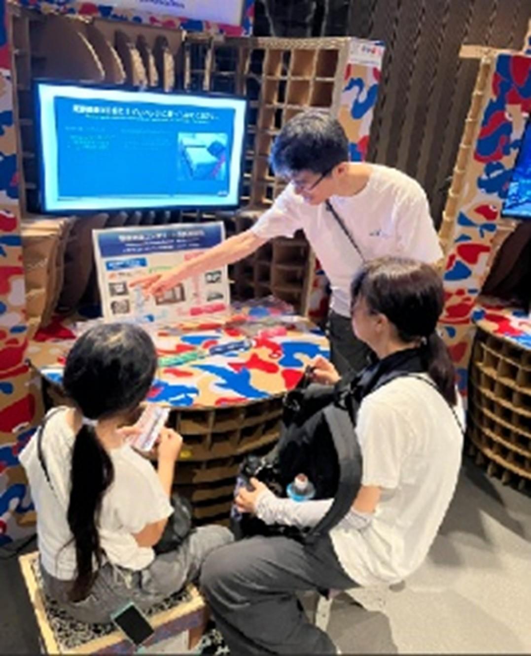 ベンチに腰掛けながら展示物の説明を受ける来訪者